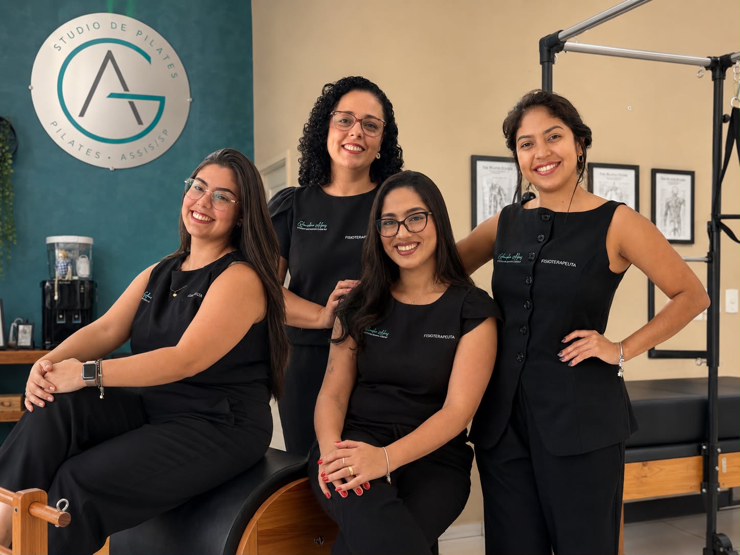 Equipe de fisioterapeutas da GA Pilates reunida no estúdio, ao lado do logo da marca